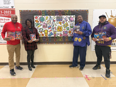 four adults holding books in hands